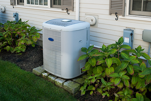 Air conditioner repair in Sea Girt, Condenser shown on well manicured lawn with bushes trimmed away from unit.